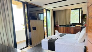 A modern hotel room with a bed, a desk, a kitchenette, and a sliding glass door to a balcony. - Hotel El Mejor (San Patricio Melaque)