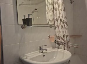 A bathroom with a white sink, a mirror, a shower with a patterned curtain, and a soap dispenser on the wall. - Villas Casa Bianca & Maria Residence (Marcana)