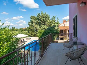 A balcony with a pool, outdoor furniture, and a view of a building and trees. - Villas Casa Bianca & Maria Residence (Marcana)