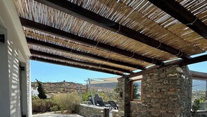 Eine Terrasse im Freien mit Tisch und Stühlen, einer Steinmauer und Blick auf die Landschaft.