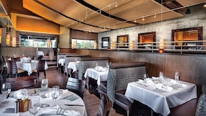 A restaurant with booths and tables, wooden ceiling, and large windows.