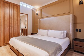 Een slaapkamer met een groot bed, een houten garderobe en een nachtkastje.