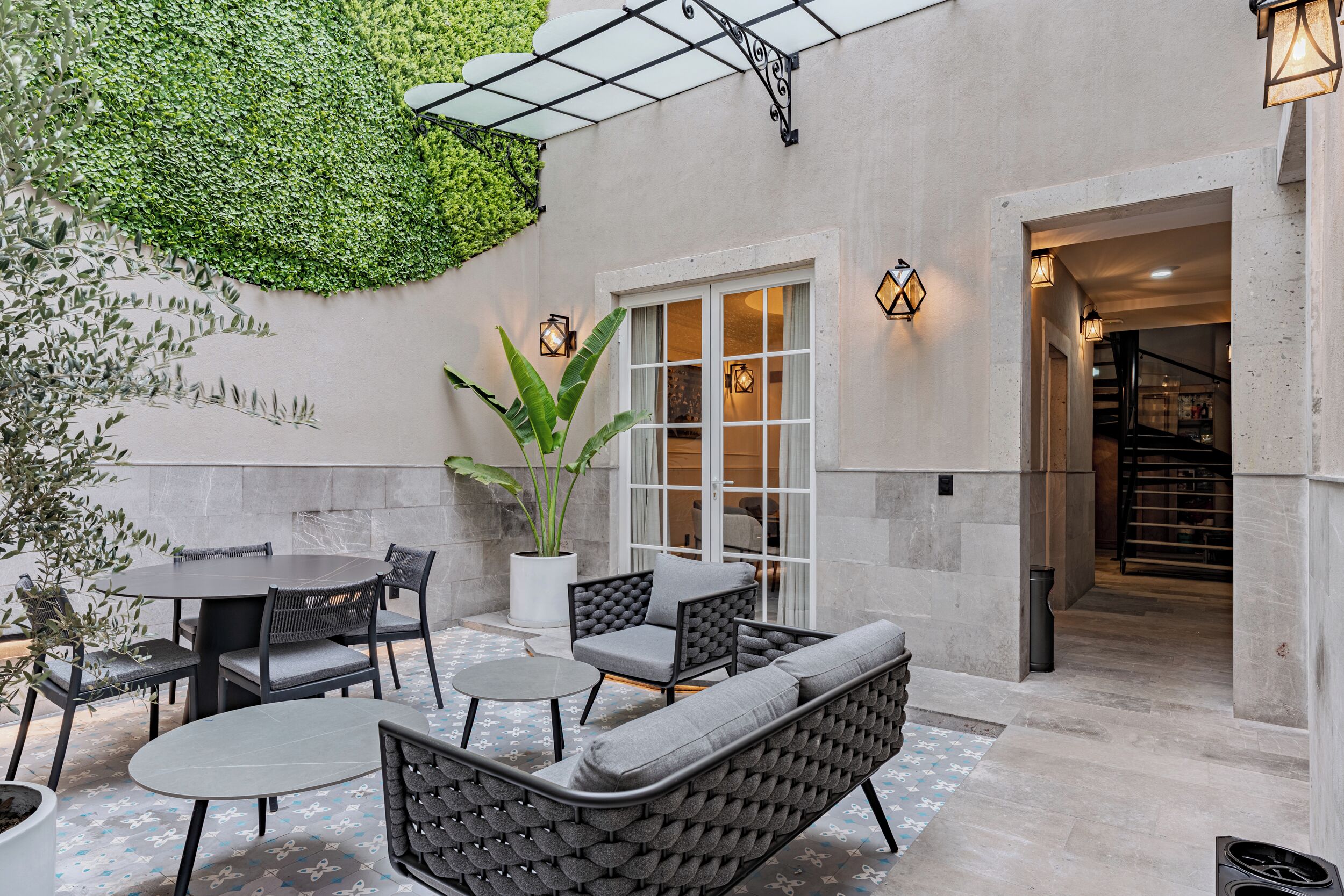 A patio with a round table, two chairs, a sofa, and a potted plant.
