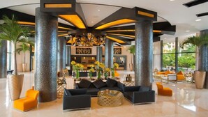 A spacious lobby with high ceilings, large columns, and a central seating area with sofas and a coffee table. - 1BR Suite – Beachfront Cancun, Pools & Ocean Views (Punta Sam)