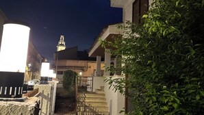 Nachts beleuchtete Straßenszene mit einem Gebäude, einer Treppe und einem weiter entfernten Turm.