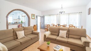 A living room with two sofas, a coffee table, and a dining area with chairs and a table. - El Almendro Cómpeta by Ruralidays (Málaga)