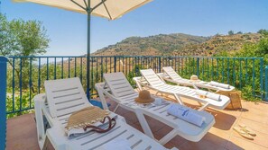 A terrace with white lounge chairs, a table with a hat and a bag, and a view of a hilly landscape. - El Almendro Cómpeta by Ruralidays (Málaga)