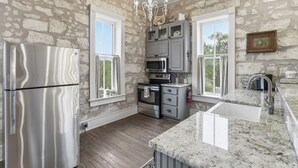 Una cocina con un refrigerador de acero inoxidable, un horno empotrado, un microondas y una encimera de granito.