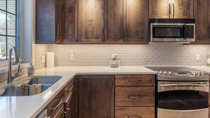 A kitchen with dark wooden cabinets, a stainless steel sink, a microwave, and an oven.