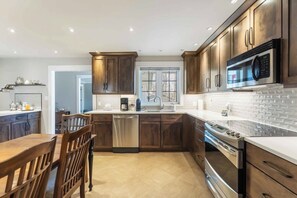 A modern kitchen with dark wood cabinets, stainless steel appliances, and a large window.