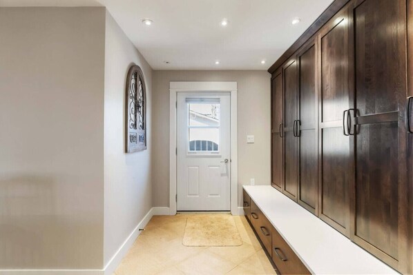 Un couloir avec une porte blanche, un tapis beige et des meubles en bois.