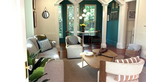 Una sala de estar con sofá, sillón, mesa de centro y comedor con mesa y sillas.