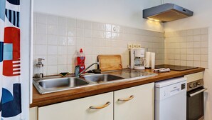 Eine Küche mit Spüle, einer Holz Arbeitsplatte, weißen Schränken und einem Geschirrspüler.