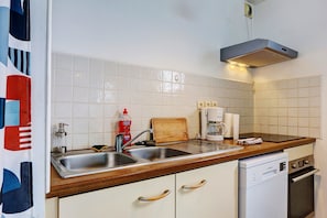 Una cocina con lavamanos, encimera de madera, armarios blancos y lavavajillas.