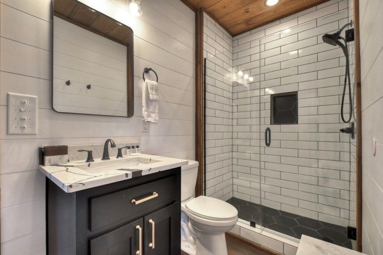 Een moderne badkamer met een dubbele wastafel, toilet en douchecabine met glazen deuren.