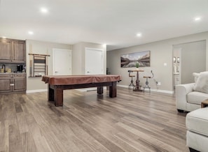 A spacious living area with a pool table, a sofa, and a painting on the wall.