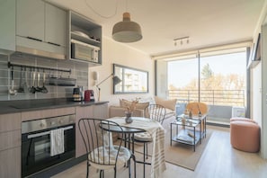 A modern kitchen with a dining area, large windows, and a view of the outdoors.