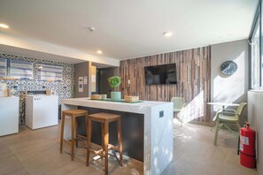 A modern kitchen with a bar area, wooden accents, and a flat-screen TV.