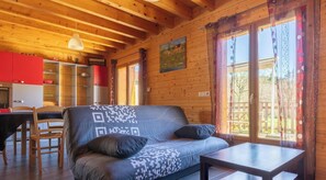 A wooden cabin interior with a sofa, dining table, and kitchen area. - Chalet du moulin - GELLES (GELLES)