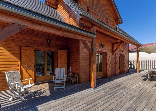A wooden cabin with a covered deck, two Adirondack chairs, and a wooden fence in the background. - Chalet du moulin - GELLES (GELLES)