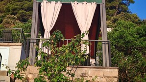 A small building with a green signboard, two curtains, and a stone base. - Green House (Mljet)