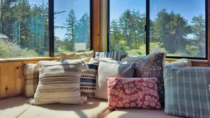 A cozy seating area with a view of a forest through large windows.
