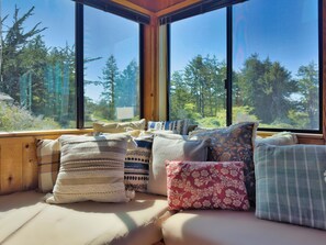 A cozy seating area with a view of a forest through large windows.