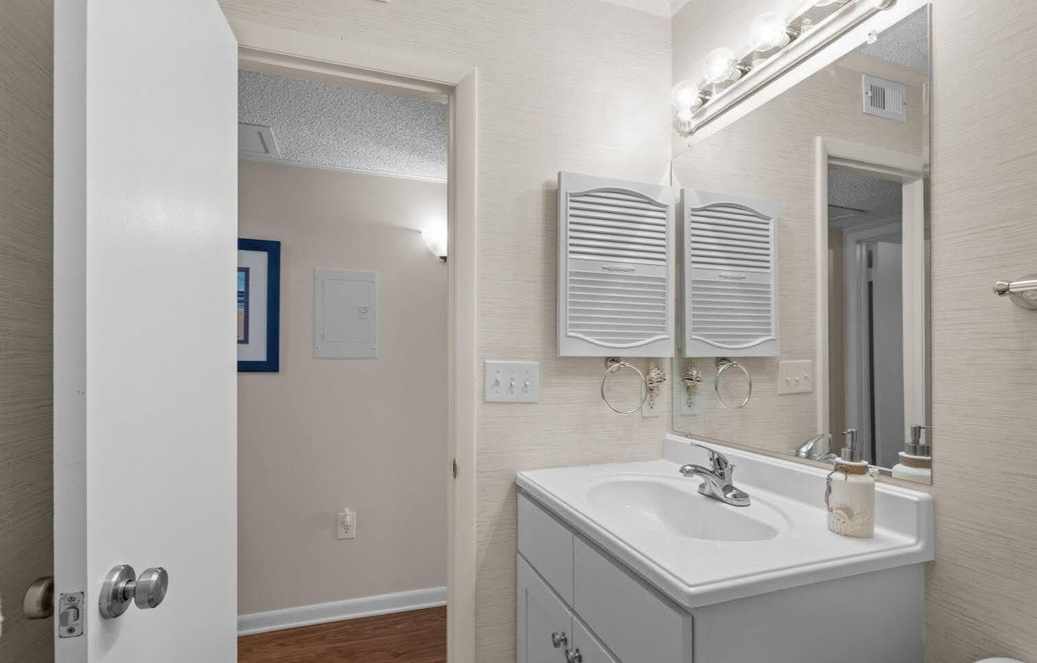A bathroom with a white vanity, a sink, a mirror, and a shower door.