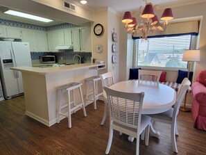 Une cuisine moderne avec des meubles blancs, un îlot central et un coin repas comprenant une table ronde et des chaises blanches.