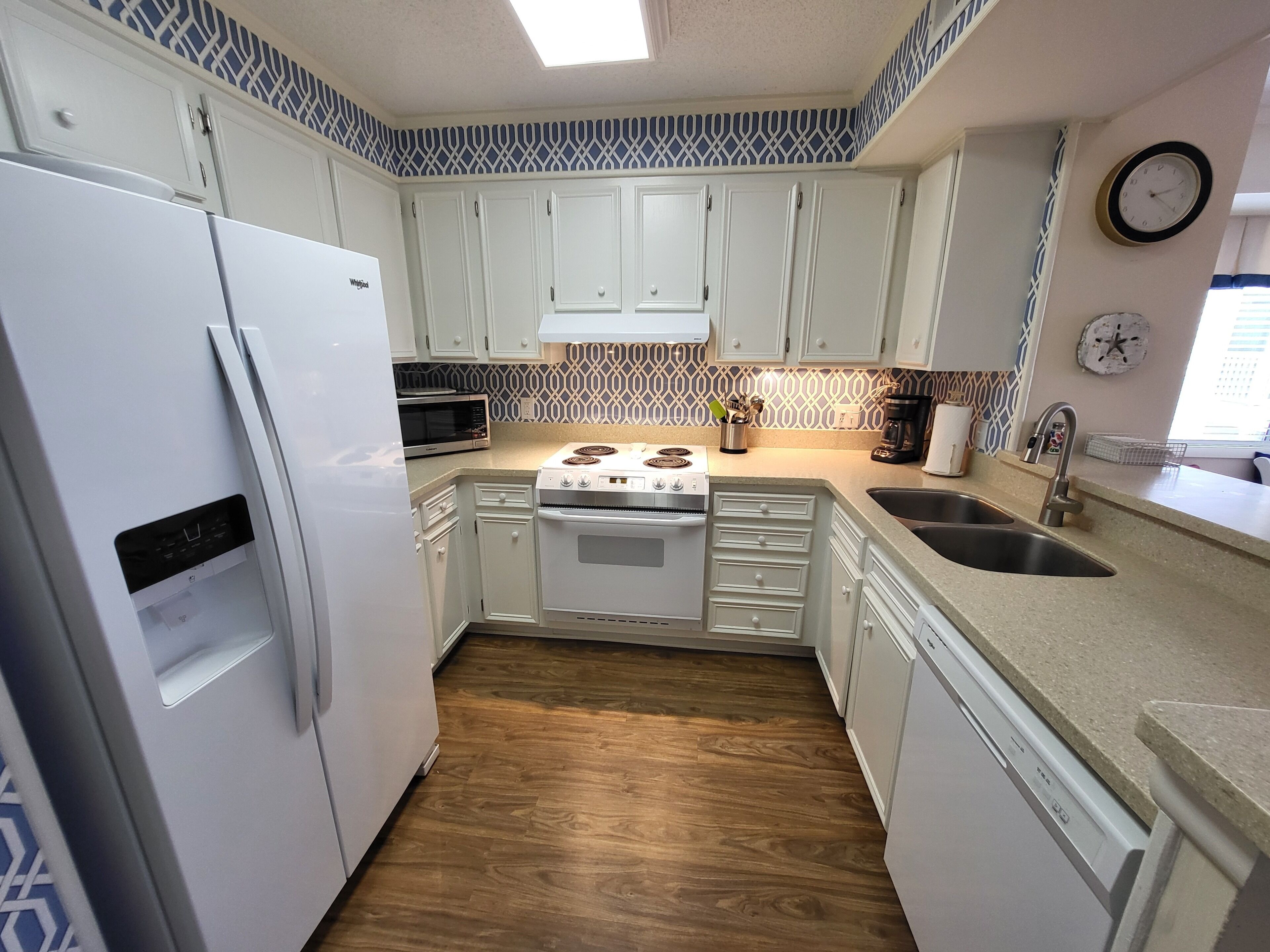 A kitchen with white cabinets, a microwave, a stove, and a sink.