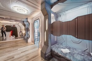 A futuristic room with a curved bed, a wooden floor, and a wall with a unique design. - Themed Kids Bedrooms | Theater Area | No Rear Neighbors (Kissimmee)