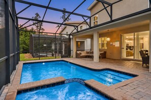 Una piscina con struttura in vetro, area relax esterna e vista sulla casa.