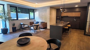 A modern kitchen with dark wood cabinets, a central island with stools, and a dining area with a round table and chairs. - HOM | Aire Acondicionado I Providencia | Parking (Providencia)