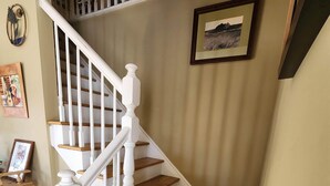 A staircase with white balusters and wooden steps, a framed picture on the wall, and a small table with a picture on it.