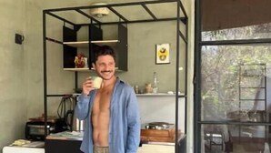 Ein Zimmer mit großem Fenster, einer Küchenzeile und einem Stehspiegel.