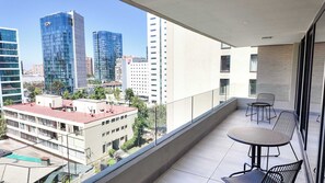 Ein Balkon mit Tisch und Stühlen mit Blick auf eine Skyline moderner Gebäude.