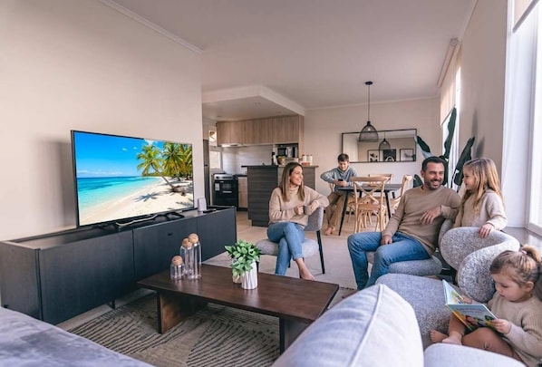 A living room with a TV displaying a beach scene, a coffee table with decorative items, and a sofa.
