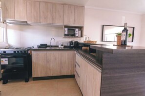 A modern kitchen with wooden cabinets, a gas stove, a microwave, and a coffee maker.