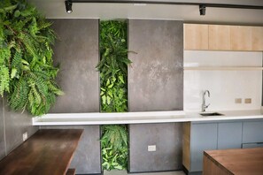 Una cocina con jardín vertical integrado, un lavamanos moderno y una encimera de madera.
