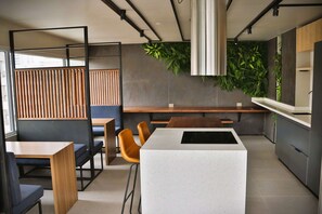 A modern kitchen with a central island, wooden seating, and green plants. - Central Apartment Near Metro & Iconic Sights w/ (Santiago)