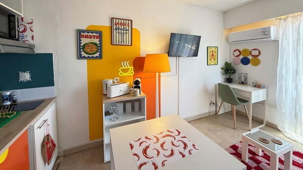 Ein modernes Wohnzimmer mit Fernseher, Sofa, Couchtisch und Schreibtisch mit Stuhl.