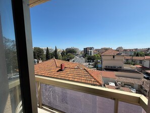 A balcony with a tiled roof, overlooking a cityscape with various buildings and a clear sky. - Studio coloré & fonctionnel – proche gare, plages & vieille ville (Antibes)
