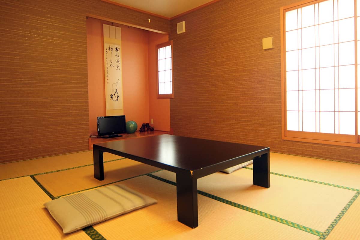 A tatami mat room with a low table, a television, and a shoji screen.