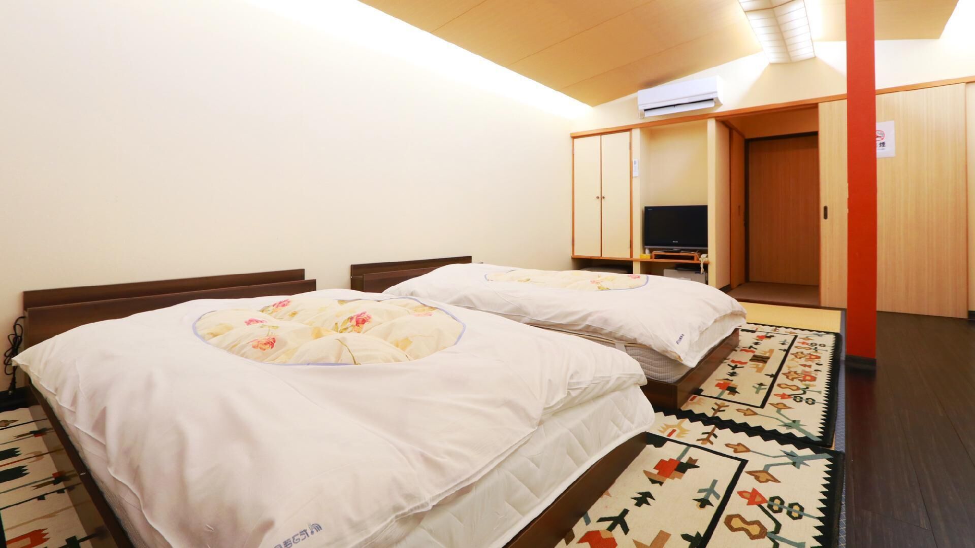 Ein Hotelzimmer mit zwei Betten, einem Fernseher und einem Kleiderschrank.