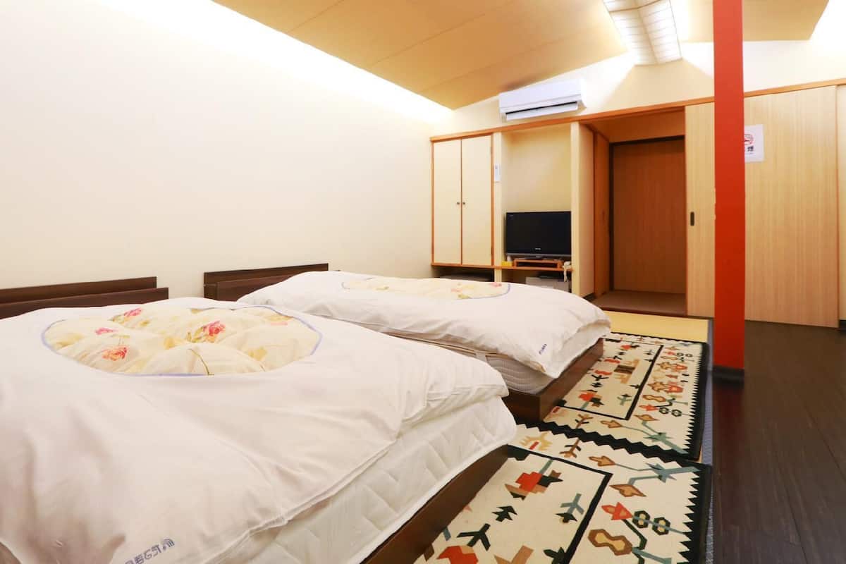 A hotel room with two beds, a television, and a wardrobe.