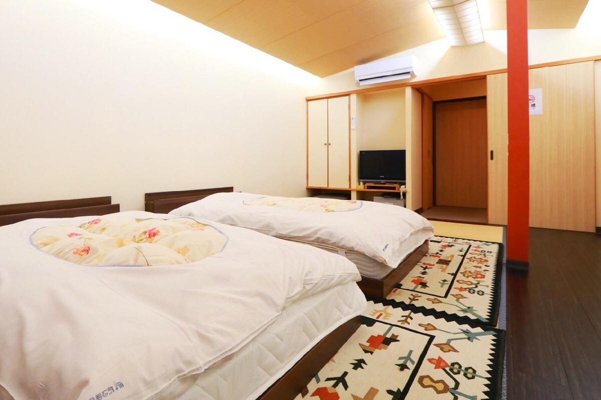 A hotel room with two beds, a television, and a wardrobe.