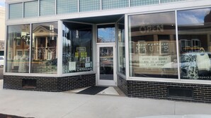 Un escaparate con grandes ventanales, fachada de ladrillo y una puerta.