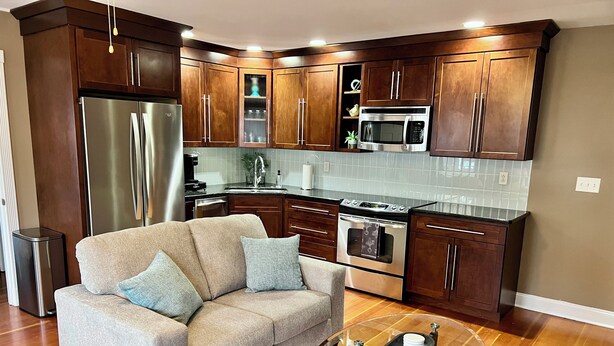 Una cocina moderna con armarios de madera, electrodomésticos de acero inoxidable y una mesa de centro de vidrio.