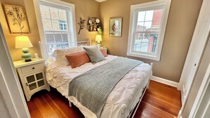 Un dormitorio con cama, mesitas de noche, una ventana y un ventilador de techo.