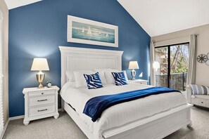 A bedroom with a white bed, blue walls, a painting of sailboats, and a balcony with a view. - Lakefront home in Osage Beach - Newly Renovated (Osage Beach)